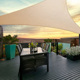 Sand triangle shade sail tensioned overhead providing shade over a courtyard dining table set.