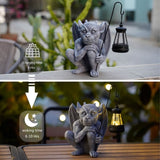 Solar gargoyle statue with glowing LED lantern illuminating an outdoor garden path at night