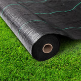 Roll of heavy duty black weed mat resting on green grass lawn prior to installation