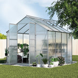 A 2.4m x 2.5m polycarbonate outdoor greenhouse with a heavy-duty aluminium frame set up in a lush Australian backyard garden.