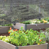 Black plastic clips securing shade netting over a garden bed with a guide rope.