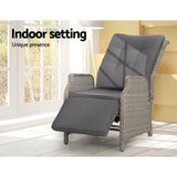 Grey wicker recliner chair used indoors beside a window with footrest extended