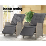 Pair of grey wicker recliner chairs used indoors with footrests extended beside a window